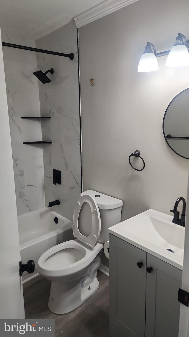 full bathroom featuring ornamental molding, vanity, tiled shower / bath combo, wood-type flooring, and toilet