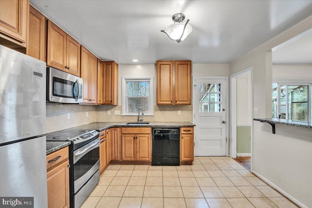 kitchen with sink, light tile patterned floors, dark stone counters, and appliances with stainless steel finishes