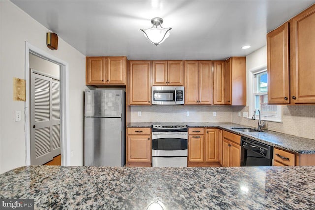 kitchen with stainless steel appliances, tasteful backsplash, dark stone counters, and sink