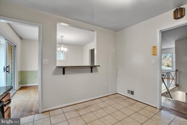 tiled empty room with a chandelier