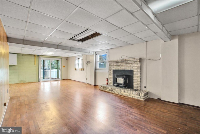 basement featuring a wood stove, a drop ceiling, and hardwood / wood-style floors