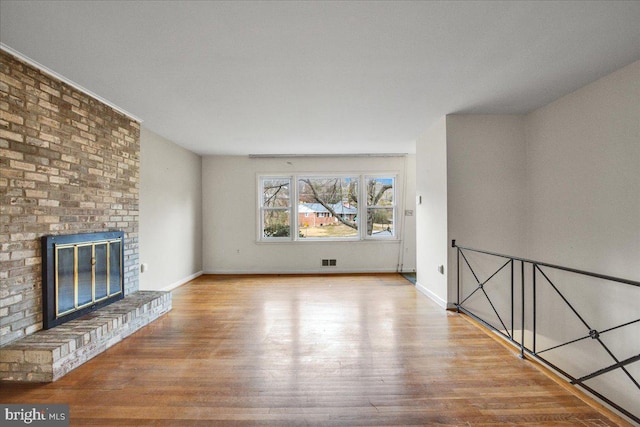 unfurnished living room with light hardwood / wood-style floors and a brick fireplace