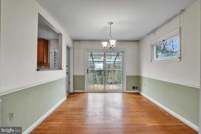 unfurnished dining area with light hardwood / wood-style flooring and an inviting chandelier