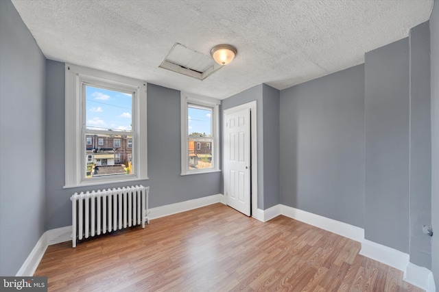 empty room featuring radiator heating unit, a textured ceiling, and light hardwood / wood-style floors