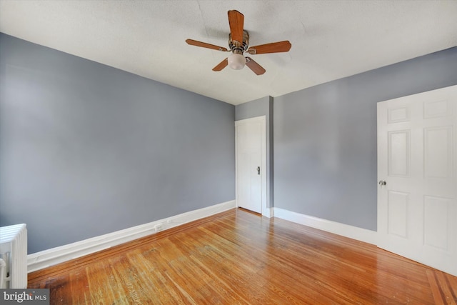 spare room featuring hardwood / wood-style floors, ceiling fan, and radiator