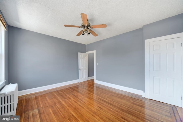 spare room featuring hardwood / wood-style floors, a textured ceiling, radiator, and ceiling fan