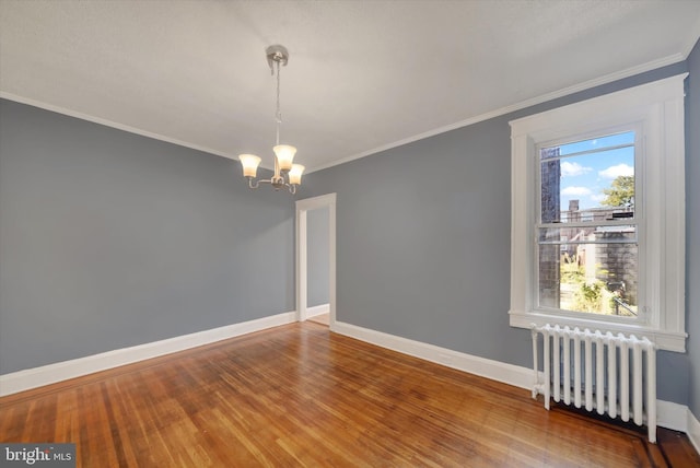 unfurnished room with radiator heating unit, hardwood / wood-style flooring, crown molding, and a notable chandelier