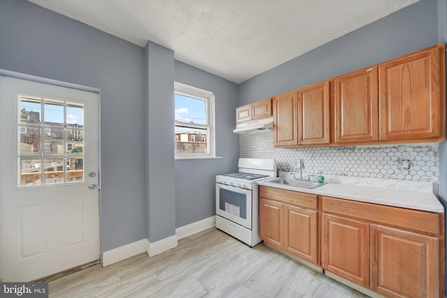 kitchen with white gas range, plenty of natural light, a textured ceiling, and sink