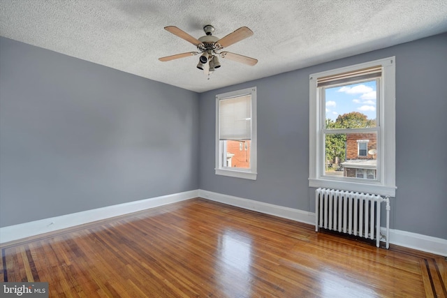 unfurnished room featuring hardwood / wood-style floors, ceiling fan, radiator heating unit, and a textured ceiling