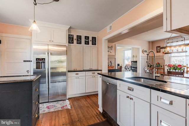 kitchen featuring decorative light fixtures, dark hardwood / wood-style flooring, white cabinetry, and stainless steel appliances