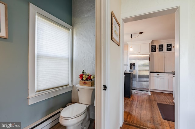 bathroom with hardwood / wood-style floors, toilet, and baseboard heating