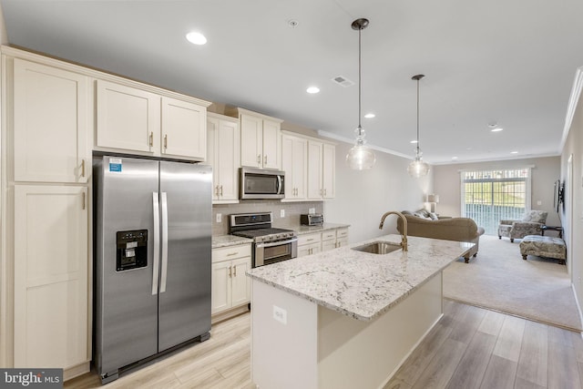 kitchen featuring sink, pendant lighting, light hardwood / wood-style floors, a center island with sink, and appliances with stainless steel finishes