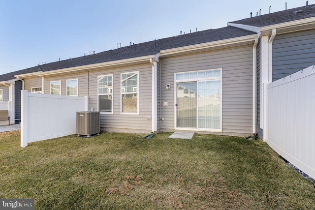 rear view of house featuring a lawn and cooling unit