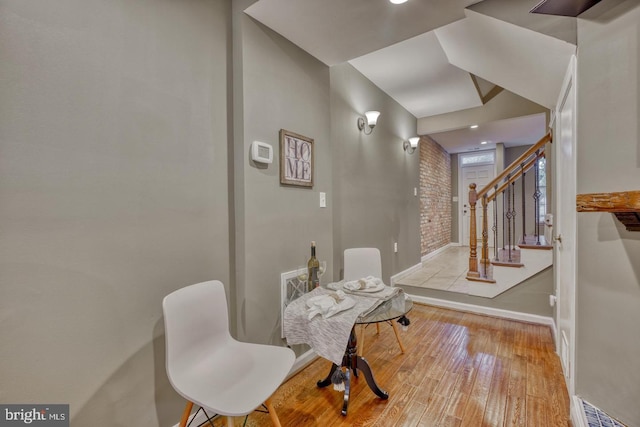 dining space featuring light hardwood / wood-style floors and brick wall