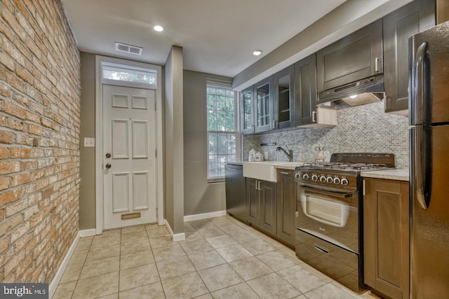 kitchen with dishwasher, sink, gas range, light tile patterned floors, and custom range hood