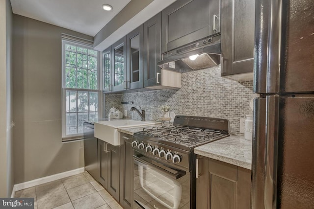 kitchen with light stone countertops, sink, stainless steel appliances, tasteful backsplash, and light tile patterned floors