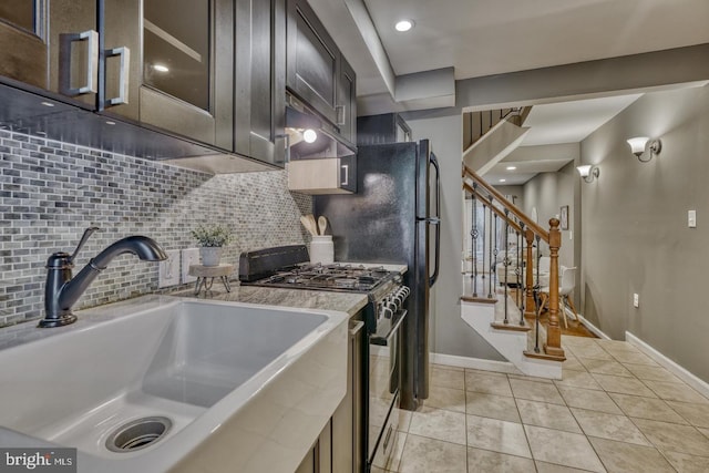 kitchen with light stone countertops, sink, tasteful backsplash, light tile patterned flooring, and stainless steel range with gas stovetop