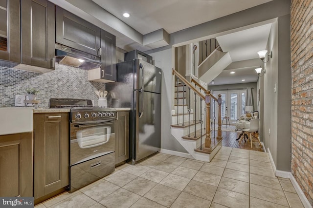 kitchen with french doors, black fridge, stainless steel range, tasteful backsplash, and brick wall