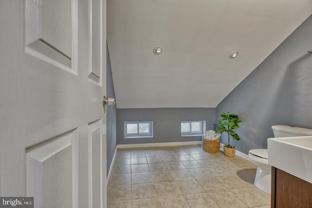 bathroom featuring tile patterned flooring, vanity, toilet, and lofted ceiling