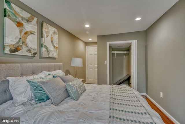 bedroom featuring wood-type flooring, a walk in closet, and a closet