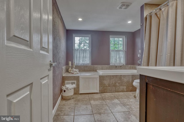 bathroom featuring tile patterned floors, toilet, and tiled tub