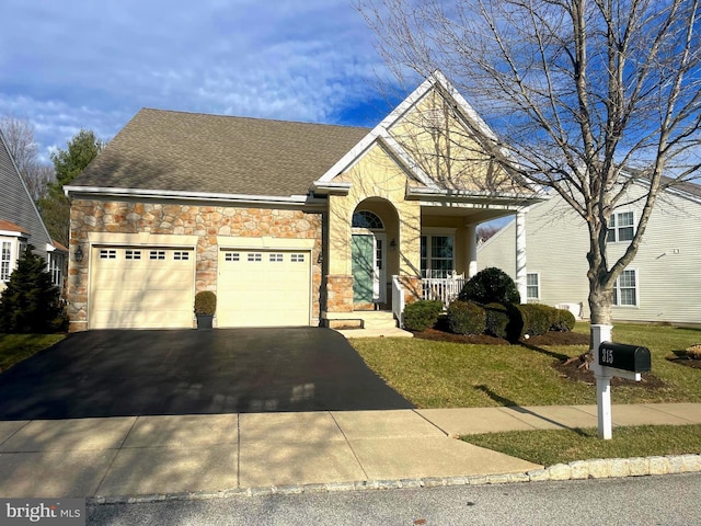 view of front of property with covered porch, a front yard, and a garage