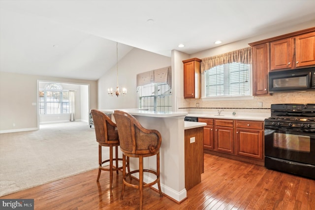 kitchen with black appliances, hanging light fixtures, decorative backsplash, a healthy amount of sunlight, and lofted ceiling