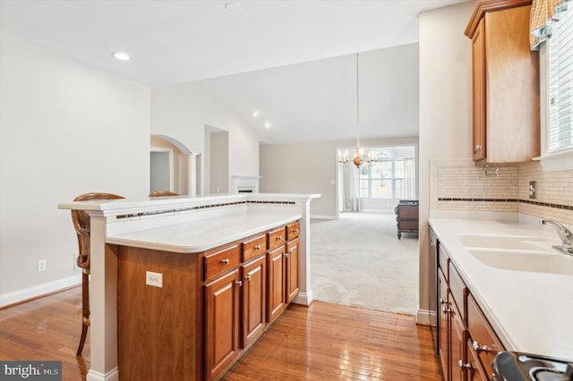 kitchen with a kitchen bar, sink, decorative light fixtures, backsplash, and vaulted ceiling