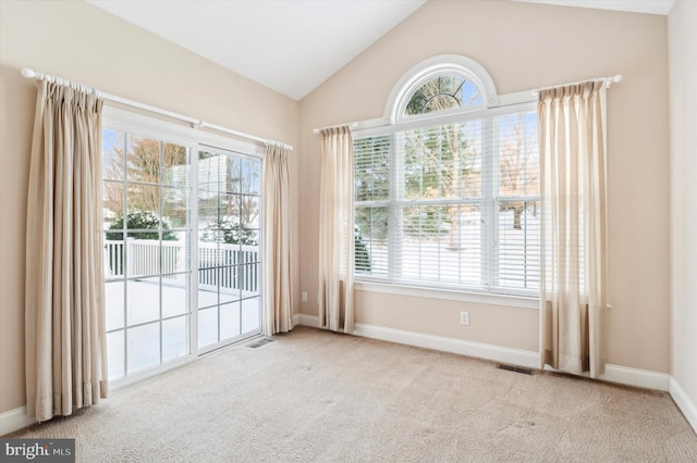 carpeted empty room featuring vaulted ceiling