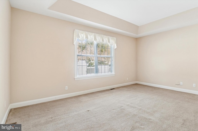 carpeted spare room with a tray ceiling