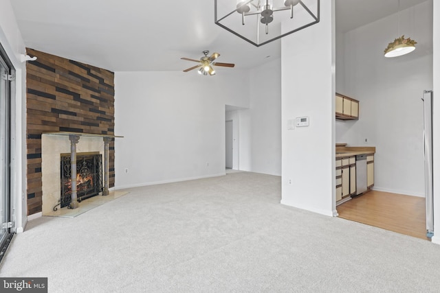 unfurnished living room featuring ceiling fan, a large fireplace, light colored carpet, and high vaulted ceiling