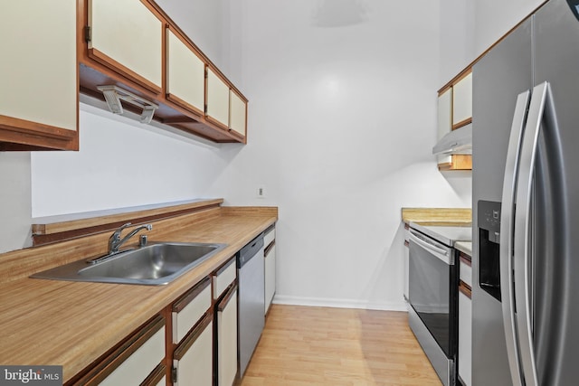 kitchen featuring white cabinets, sink, stainless steel appliances, and light hardwood / wood-style flooring