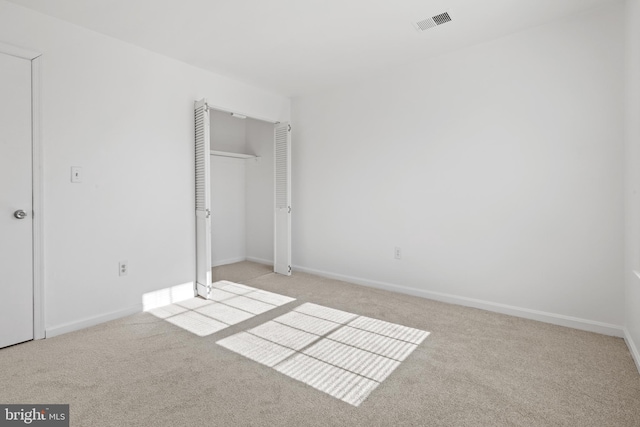 unfurnished bedroom with a closet and light colored carpet