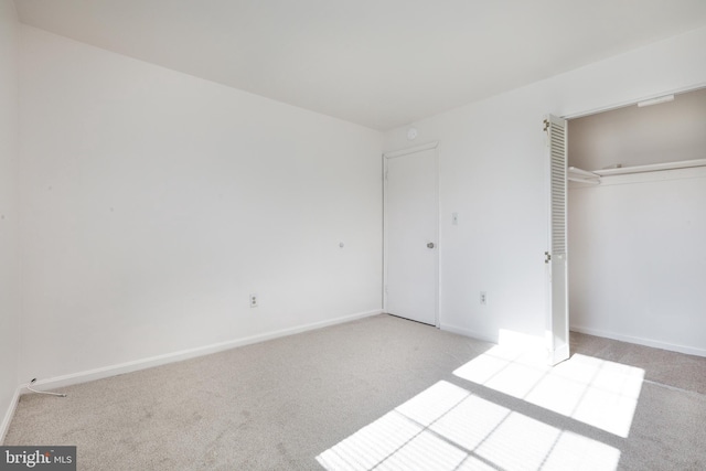 unfurnished bedroom with light colored carpet and a closet