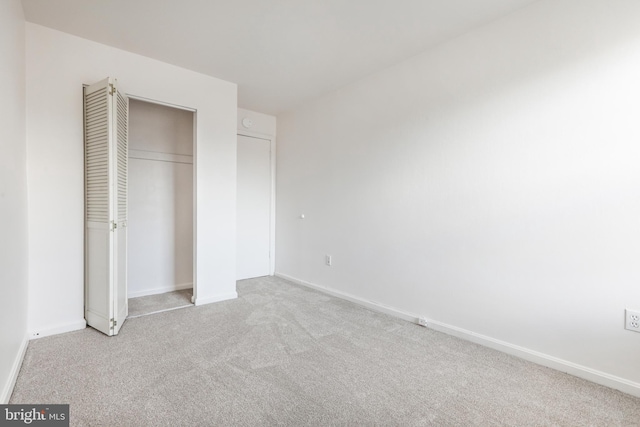 unfurnished bedroom with light colored carpet and a closet