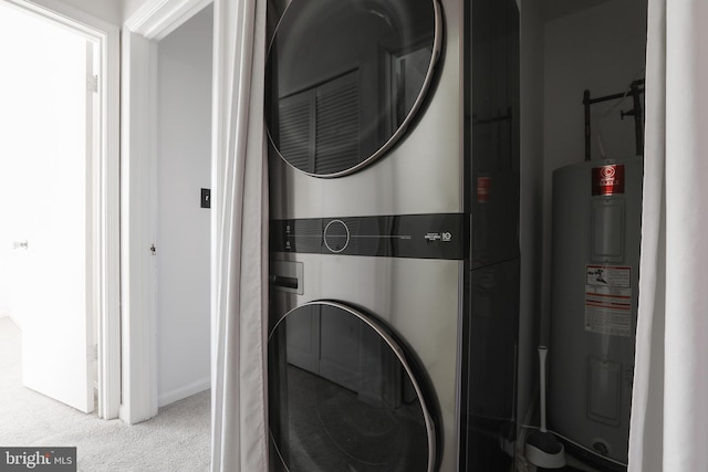 clothes washing area featuring electric water heater, light colored carpet, and stacked washing maching and dryer