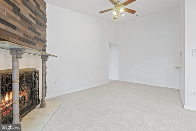 unfurnished living room featuring ceiling fan, light colored carpet, and a tile fireplace