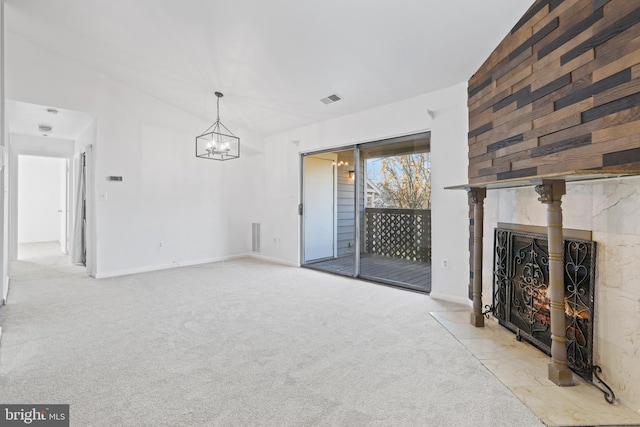 unfurnished living room with a tile fireplace, light colored carpet, and an inviting chandelier