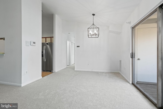 carpeted empty room featuring a chandelier