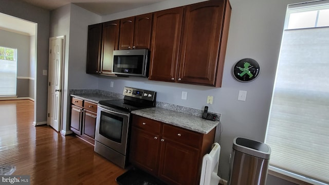 kitchen featuring radiator heating unit, stainless steel appliances, a wealth of natural light, and dark wood-type flooring