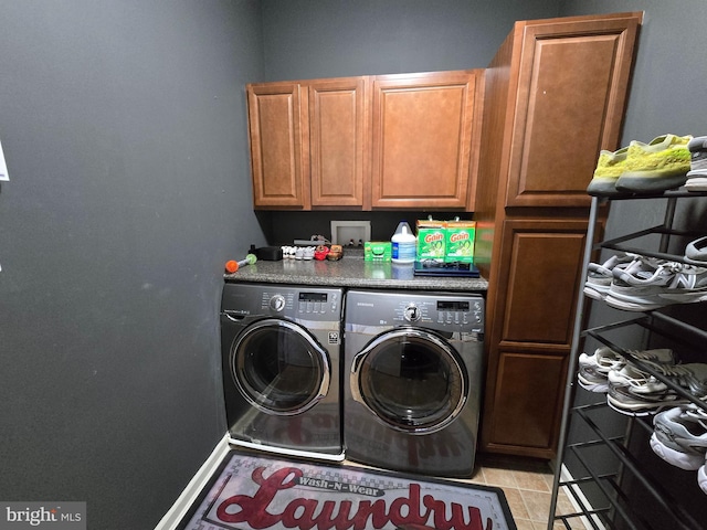 washroom featuring washing machine and dryer, light tile patterned flooring, and cabinets