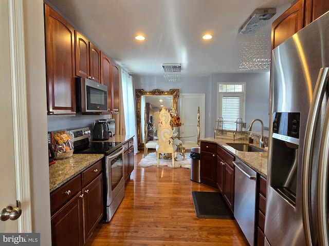 kitchen featuring dark hardwood / wood-style flooring, light stone countertops, sink, and stainless steel appliances