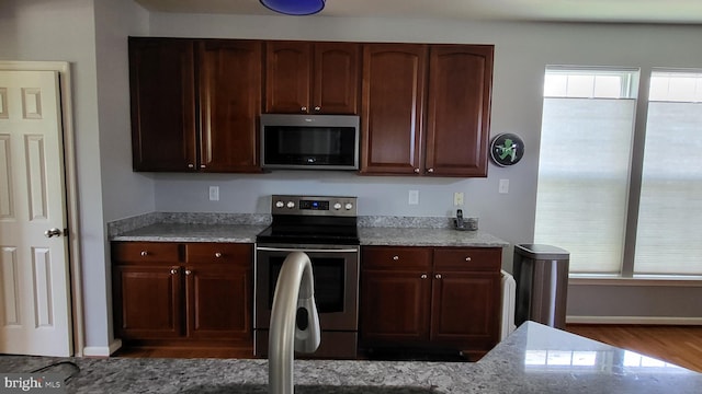 kitchen with light stone counters, hardwood / wood-style floors, and appliances with stainless steel finishes