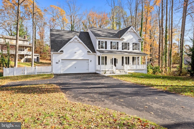 view of front facade featuring a garage, covered porch, and a front yard