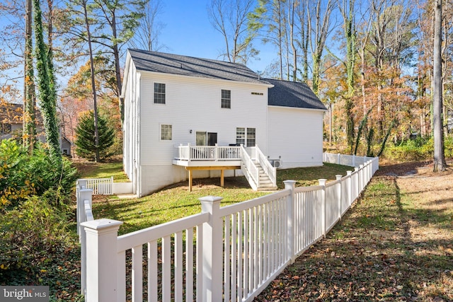 back of house featuring a lawn and a wooden deck