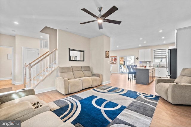 living room with ceiling fan, sink, and light wood-type flooring