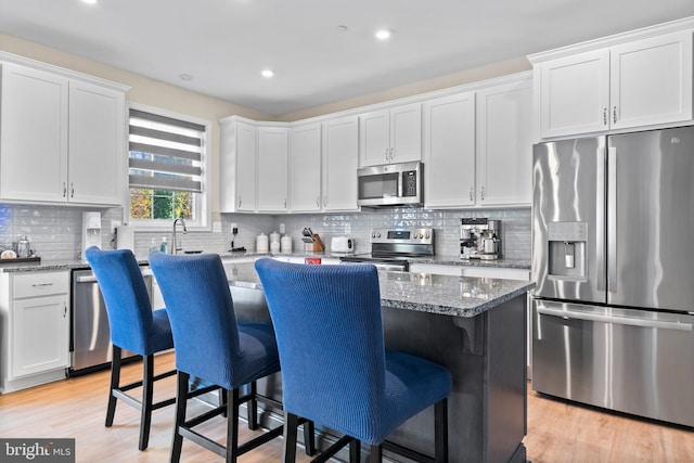 kitchen featuring a breakfast bar, white cabinets, stainless steel appliances, and a kitchen island