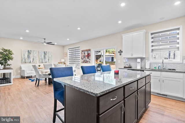 kitchen featuring white cabinets, ceiling fan, light hardwood / wood-style floors, and a breakfast bar