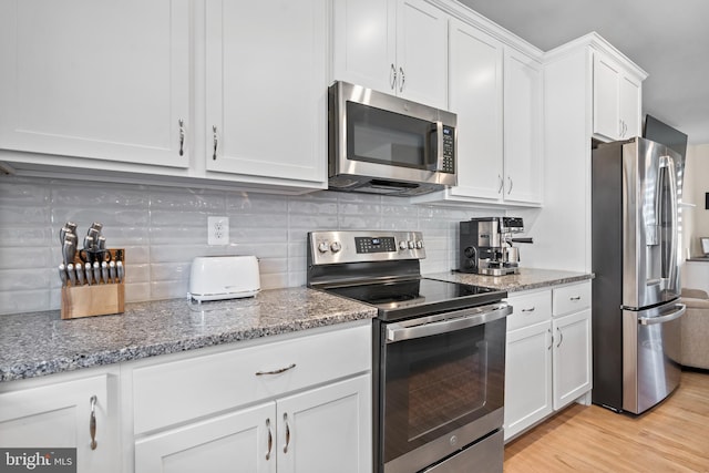 kitchen featuring stone counters, light wood-type flooring, stainless steel appliances, and white cabinetry