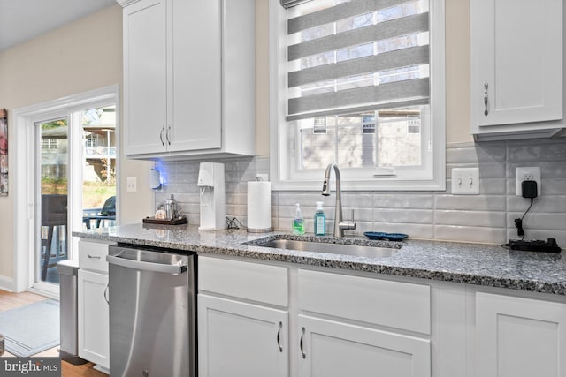 kitchen with tasteful backsplash, stainless steel dishwasher, sink, light hardwood / wood-style flooring, and stone counters